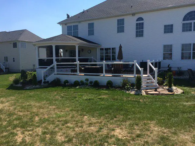A picturesque white house with a lovely deck and inviting porch, perfect for enjoying the outdoors in comfort.